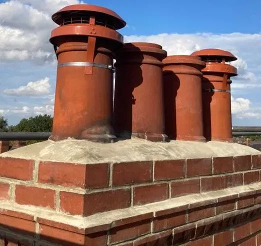 Chimney stack being repointed with fresh mortar and lead flashing