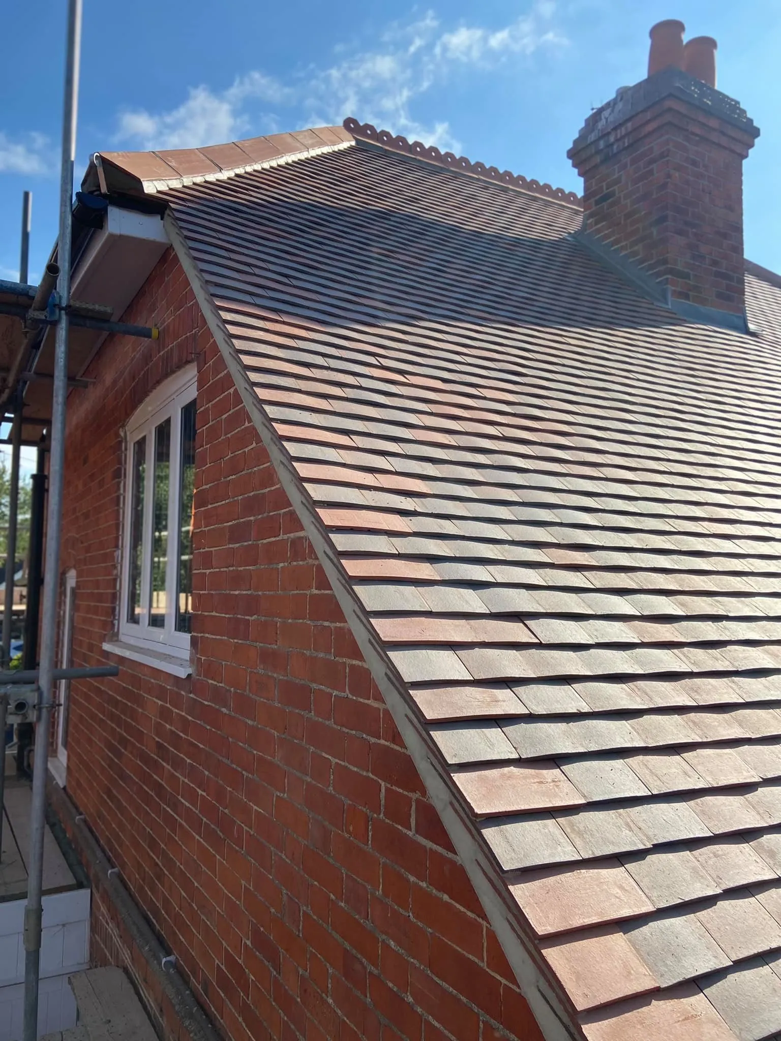 Red brick British house with completed slate roof